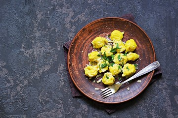 Pumpkin dumplings or gnocchi with parmesan cheese, butter and parsley on a brown clay plate. Harvest pumpkins. Thanksgiving Day. Top view, copy space. Italian food.
