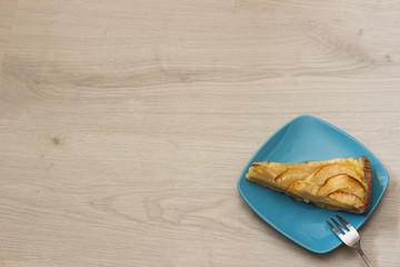 Portion of apple pie on a turquoise plate with fork