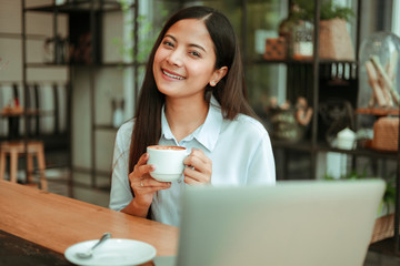 Asian woman in blue shirt working and drink coffee in coffee shop cafe vintage color tone