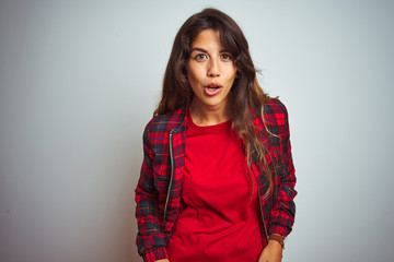 Young beautiful woman wearing red t-shirt and jacket standing over white isolated background afraid and shocked with surprise expression, fear and excited face.