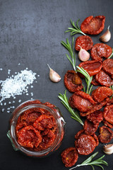 Sun dried tomatoes in a glass jar on a dark background. The classic recipe for Mediterranean cuisine. Place for text