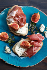Sandwich with ham, blue cheese and figs on a blue dish