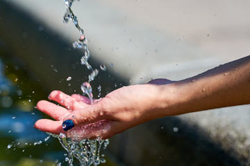 Fototapeta na wymiar Woman´s hand under a fresh stream of water in sunlight. 
