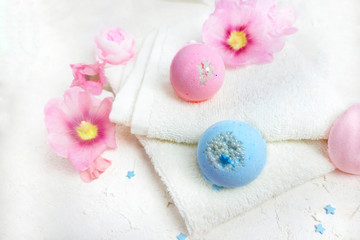 Obraz na płótnie Canvas Bath bombs with towel and flowers on white background. Spa life style concept for relax. Selective focus. Copy space.
