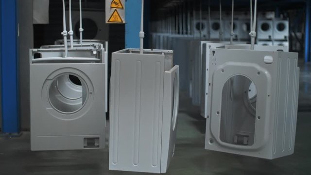 Washing machine carcase moving on automatical conveyor at modern factory