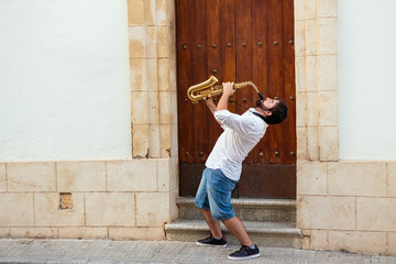 Portrait of a man passionately playing the saxophone at the door of a building on the street