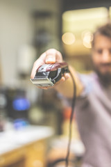 Close up of fashionable hipster hairdresser holding hair trimmer.