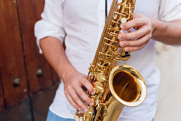 Close up of a man passionately playing the saxophone at the door of a building on the street