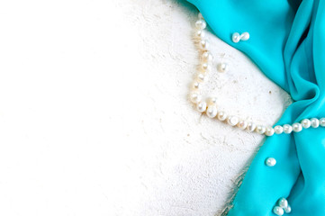 Drapped blue silk fabric with pearl beads on white background. Pretty wedding decorative concept. Banner.