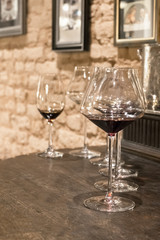 Glasses of red wine are on the bar.