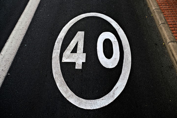 Forty, number 40, speed limit information painted in white reflective paint on black asphalt surface.