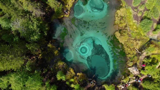 Beautiful Geyser lake with thermal springs that periodically throw blue clay and silt from the ground. Aerial drone view. Aktash, Altai mountains, Russia