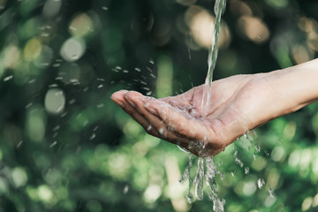 closeup water flow to hand of women for nature concept on the garden background.