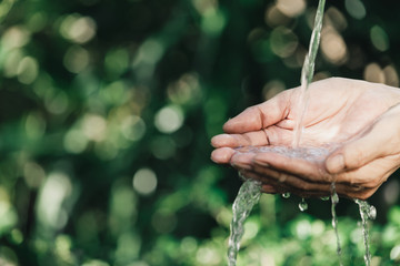 closeup water flow to hand of women for nature concept on the garden background.