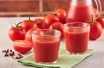 Tasty Tomato juice in a glass with ripe red tomatoes.