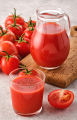 Tasty Tomato juice in a glass with ripe red tomatoes.
