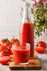 Tasty Tomato juice in a glass with ripe red tomatoes.