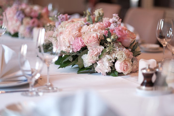 Bouquet on the table. Wine glasses in the foreground. Wedding Banquet or gala dinner. The chairs and table for guests, served with cutlery and crockery.
