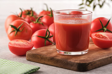 Tasty Tomato juice in a glass with ripe red tomatoes.