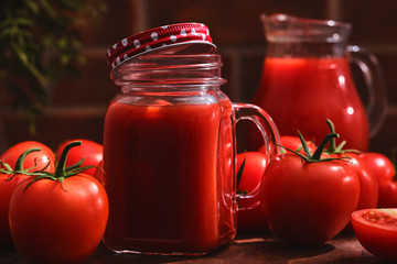 Tasty Tomato juice in a mason jar with ripe red tomatoes.