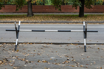 Black and white metal fence stands to prohibit the passage of cars on the side of the road with...