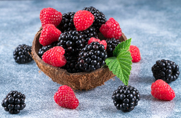 Mix of fresh berries with leaves on blue  background