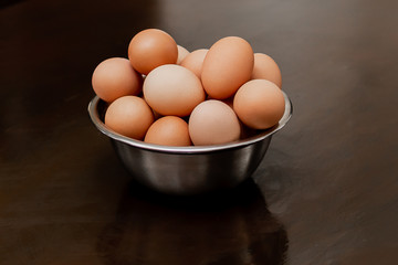 Raw eggs in metal bowl on a wooden table