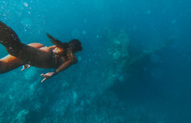 Discovering a japanese ship wreck from second world war. Beautiful woman swimming underwater in a...