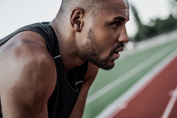 Close up side view shot of young african sportsman relaxing after running