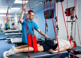 Physiotherapy. Suspension training therapy. Young man doing fitness traction therapy with...