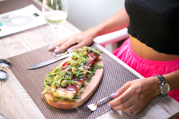 Girl eating prosciutto and rucola in restaurant