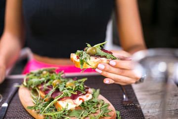 Girl eating prosciutto and rucola in restaurant