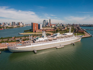 aerial of SS Rotterdam ship moared on Katendrecht land head with skyline of towers and Erasmus bridge in the background  - obrazy, fototapety, plakaty