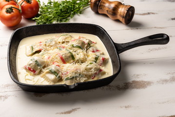 Handmade color ravioli pasta; Multi-colored ravioli pasta in a black iron pan, on wooden white table background.