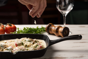Handmade color ravioli pasta; Multi-colored ravioli pasta in a black iron pan, on wooden white table background.