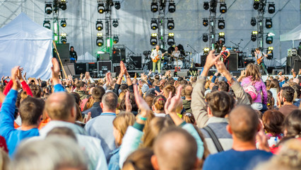 many different people at a concert listening to rock band music open air