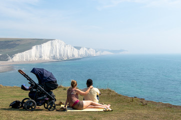 Couple and child sitting on a cliff at Seven Sisters by the English Channel
