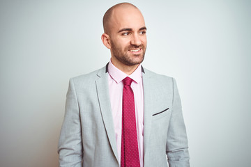 Young business man wearing suit and purple tie over isolated background looking away to side with smile on face, natural expression. Laughing confident.