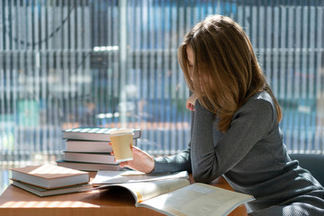 european beautiful schoolboy girl resting and drinking coffee in school library