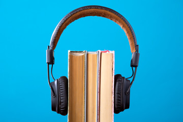 headphones and books but against blue background, concept of audio books, listening to a book