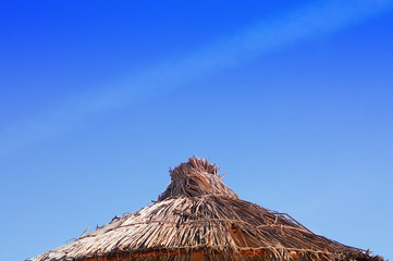 Fototapeta na wymiar Strandschirm oben fotografiert mit hellblauem Himmel im Hintergrund.