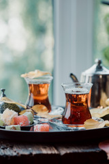 Glass Cup of turkish tea served in traditional style with summer outdore view