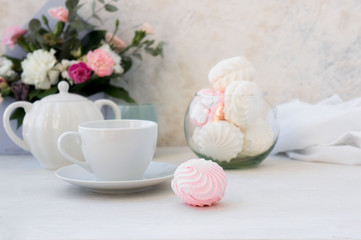 Homemade white and pink marshmallow zephyr with cup of tee on a white table. Selective focus.