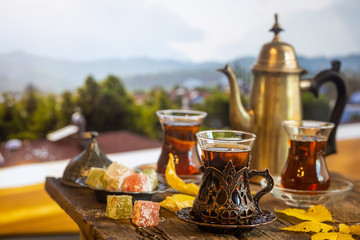Glass Cup of turkish tea served in traditional style with summer outdore view