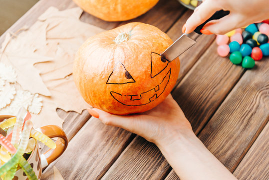 View of female hands carve with knife a pumpkin for Halloween holiday.