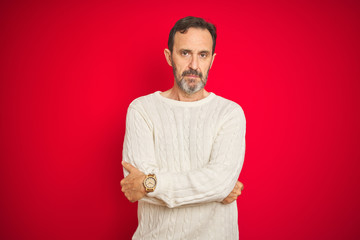 Handsome middle age senior man with grey hair over isolated red background skeptic and nervous,...