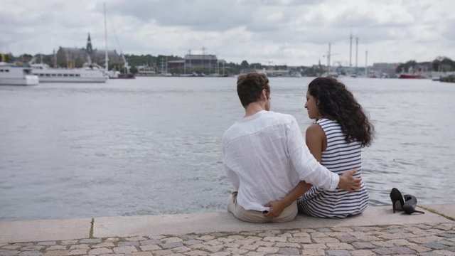 A young loving couple relaxing and smiling in a harbour in Stockholm centre.