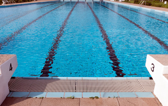 Startbl&ouml;cke am Beckenrand von einem Schwimmbad. Die Bl&ouml;cke tragen die Nummer drei und vier. Die Startbl&ouml;cke werden f&uuml;r Schwimmwettbewerbe genutzt .