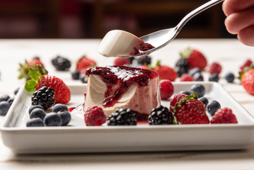 Delicious italian dessert panna cotta with berry sauce, fresh berries on white wooden background
