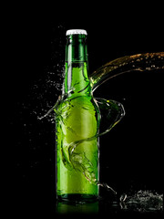 Green beer bottle splash on black background